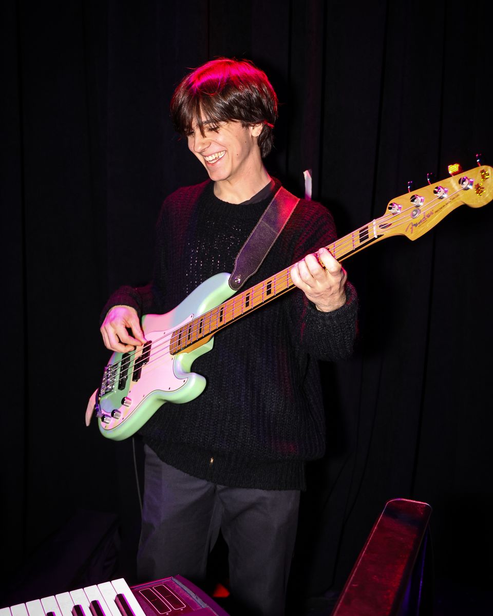 Bassist with a pastel guitar smiling on stage