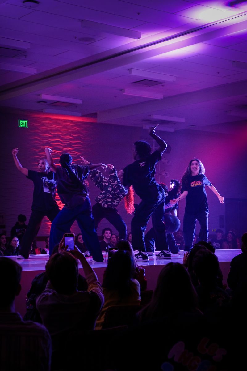 Dancers mid-move on the runway under violet light