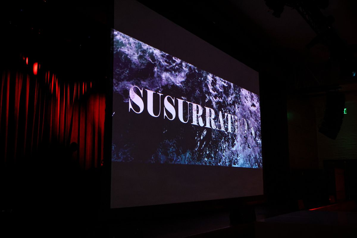 The short film Susurration projected beside red curtains