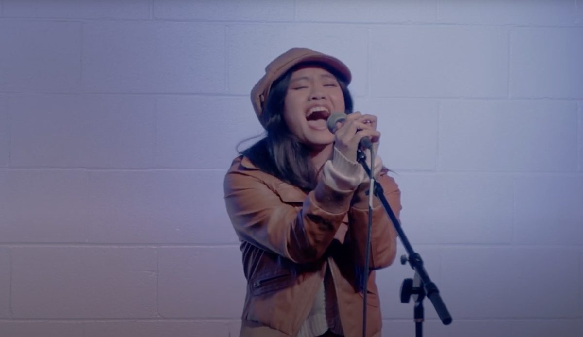 Performer in a newsboy cap belting into the microphone