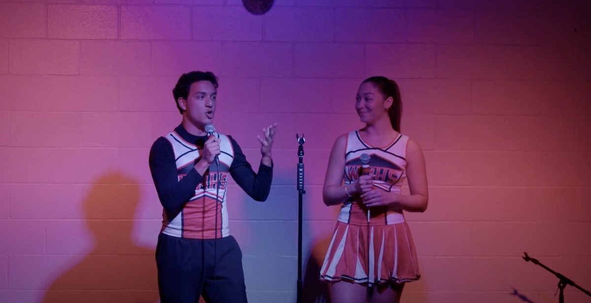 Two performers in cheerleader costumes trading lines